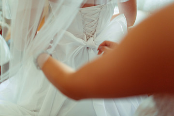 Woman's hands ties a bow on a wedding dress