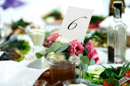 Number six printed on the white paper stands in the bouquet