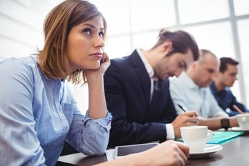 Thoughtful businesswoman with colleagues in meeting room