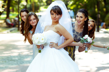 Bridesmaids hide behind a bride while she stands in the foregrou