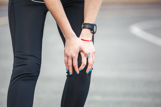 Female runner is holding her injured leg.