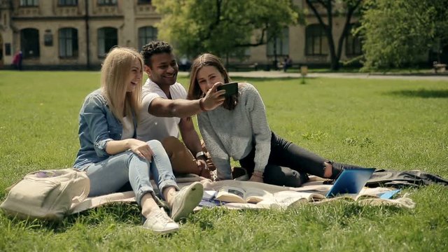 Students making selfies on the phone on lawn.