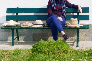 woman on a bench surrounded by hats