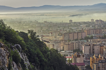 Picturesque cityscape of residential districts and suburbs of the Brasov city, Romania, on a foggy early morning.