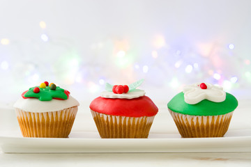 Christmas cupcakes and lights on white wooden table

