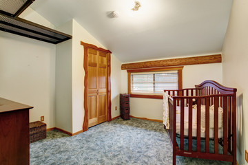 Interior of nursery room with baby crib in log cabin house.