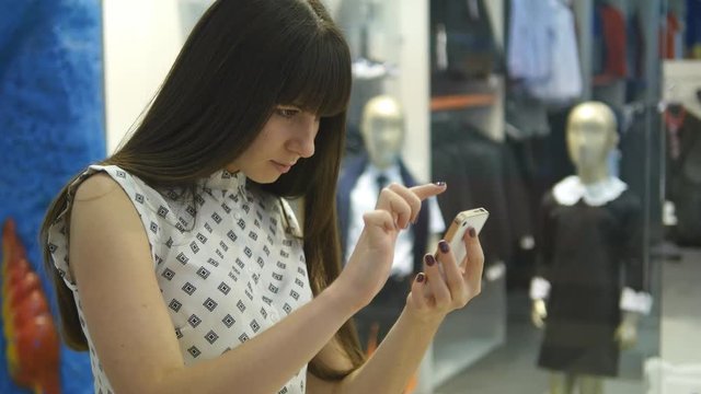 Young woman playing indoor at shopping center, using smart phone. Girl play the popular smartphone game