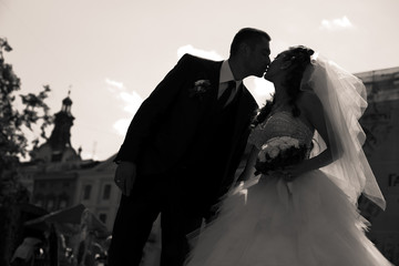 A black and white picture of groom leaning to bride to kiss her