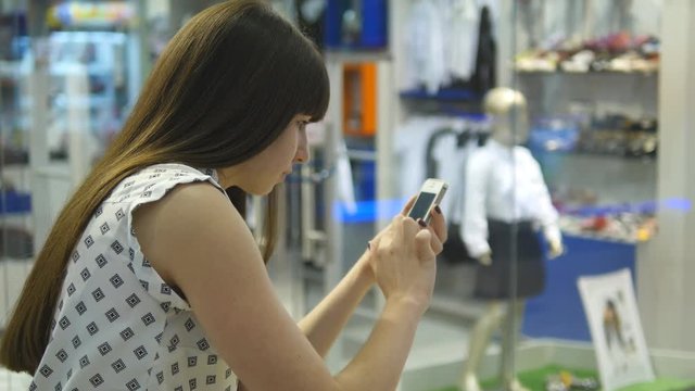 Young woman playing indoor at shopping center, using smart phone. Girl play the popular smartphone game