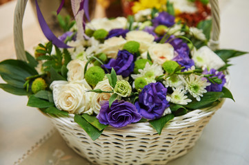beautiful bouquet of white and purple flowers in basket on wooden table