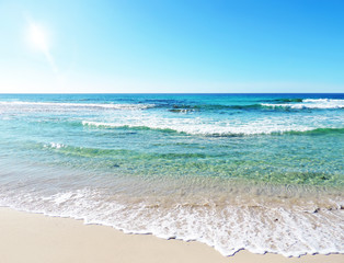 Fototapeta na wymiar Beach scene with turquoise water, blue sky and sunbeam over the sea.