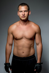 Fototapeta na wymiar Vertical portrait of a sports man with a naked torso on a gray b