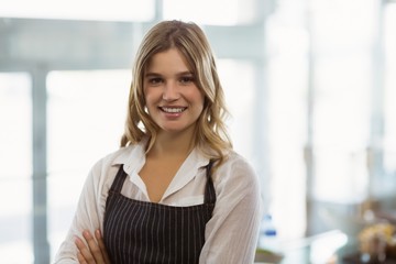 Portrait of smiling waitress standing with arms crossed