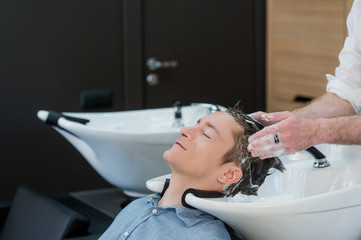 Close-up of a young man having his hair washed in hairdressing salon