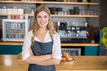 Portrait of smiling waitress standing with arms crossed - obrazy, fototapety, plakaty