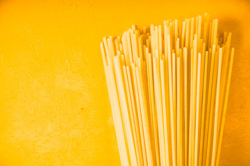 Raw spaghetti on the yellow background horizontal