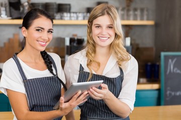 Portrait of two smiling waitresses using digital tablet