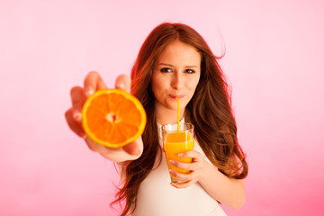 Woman drinking orange juice smiling showing oranges. Young beaut