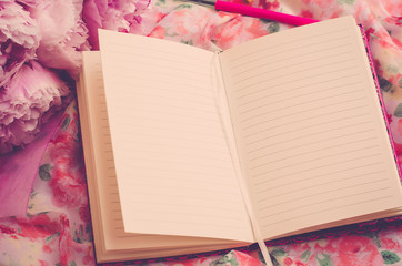 Open pink notebook on a beautiful pink background. Flowers near the notepad (vintage)