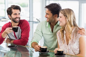 Smiling woman and two men having cup of coffee