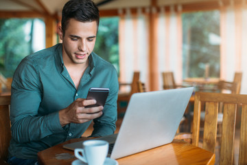 Young man sitting at cafe and using mobile phone