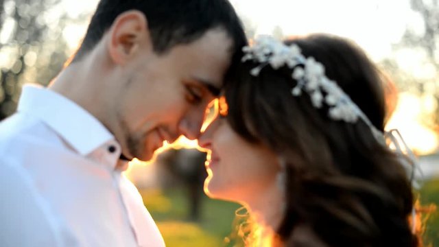 Beautiful young couple bride and groom embracing and kissing at sunset.