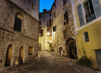 Fototapeta na wymiar Narrow cobbled street in old town Peille at night, France.