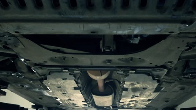Bottom of the car and exhaust pipe 4K zoom in shot. Car maintenance at service station