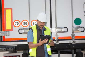 Portrait of delivery man smiling using digital tablet by truck