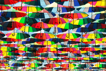 Colorful umbrella with colors of rainbow in the blue clear sky. Conceptual bright background.