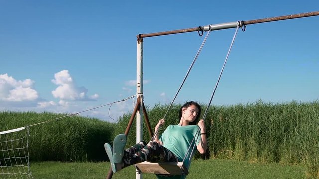 Beautiful young woman swinging outdoors