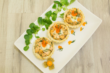 Salmon baked tartlet with mozzarella on a white plate