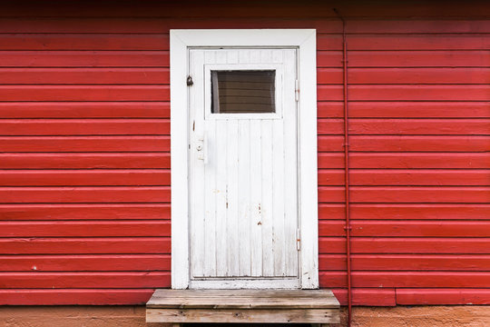 Small white closed door in red wooden wall