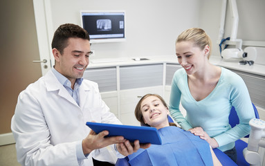 Obraz premium dentist showing tablet pc to girl and her mother