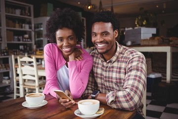 Young couple using mobile phone in cafeteria
