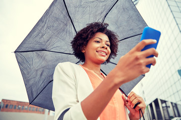 businesswoman with umbrella texting on smartphone