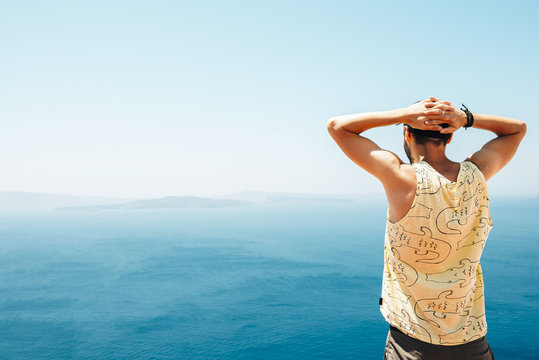 Greece, Santorini, back view of man with hands behind his head looking to the sea