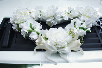 The garland of white flowers lies on the car