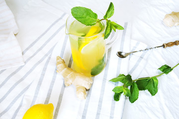 Lemonade with ginger and mint in kitchen. Home made ginger lemonade on striped napkin or towel. Healthy drink lemonade.