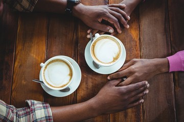 Couple holding hands while having coffee