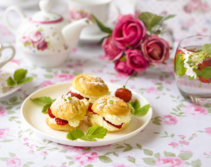 Cream puff cakes or profiterole filled with whipped cream,g served with strawberries