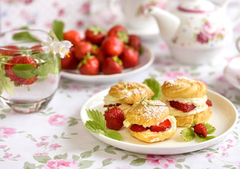 Cream puff cakes or profiterole filled with whipped cream,g served with strawberries