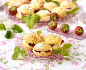 Cream puff cakes or profiterole filled with whipped cream,g served with strawberries