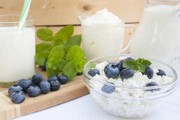 Culinary cottage cheese with bilberry and fresh mint in a class bowl on the table with other dairy products