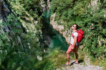 Obraz premium Man standing on mountain cliff over the river