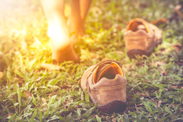 Child take off shoes. Child's foot learns to walk on grass with sunlight