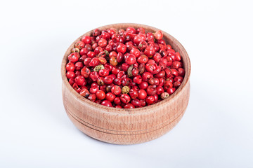 Pink pepper in a wooden bowl isolated on white background