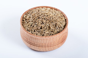 Cumin seeds or caraway in a wooden bowl isolated on white background