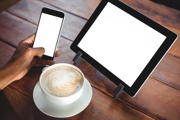 Woman using mobile phone and digital tablet in cafe