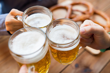 close up of hands with beer mugs at bar or pub
